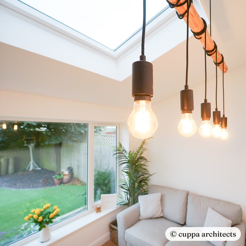 Filament pendant lights under a rooflight beside a wide garden window