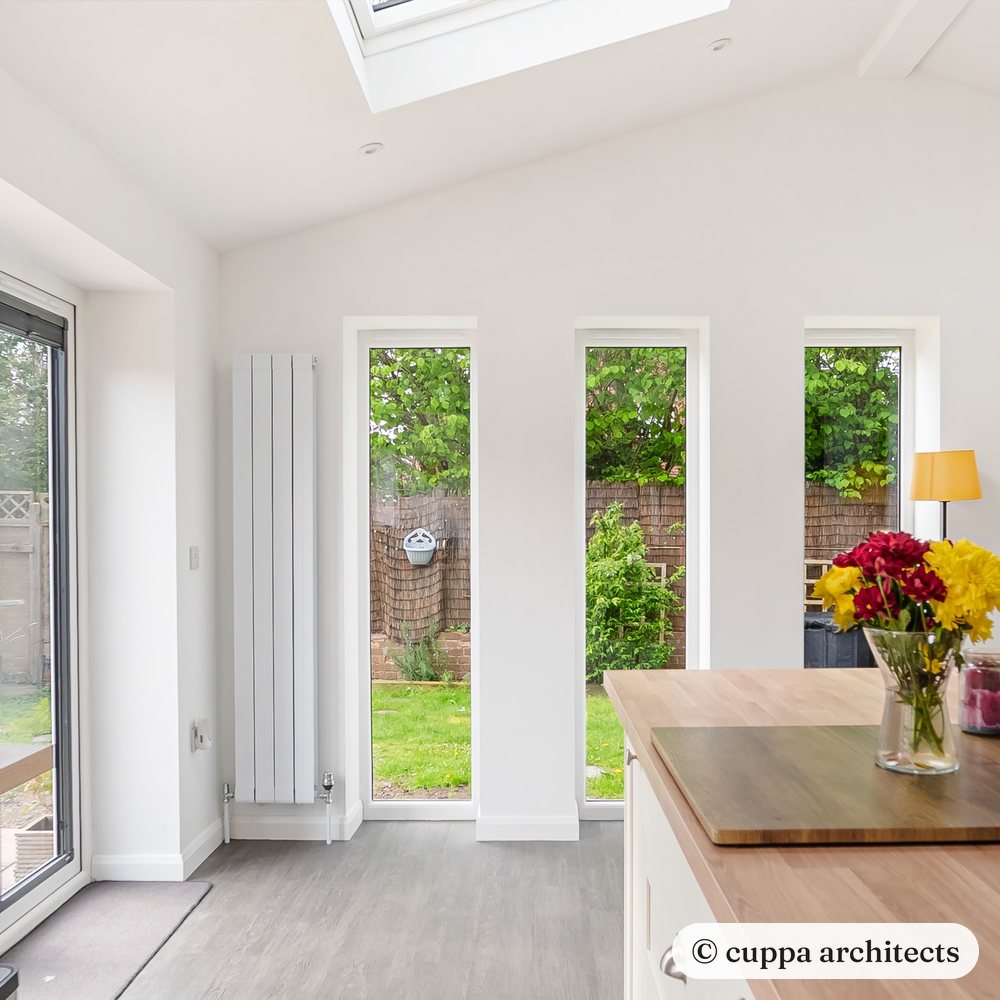 Tall slim windows looking out to the garden beside an oak worktop