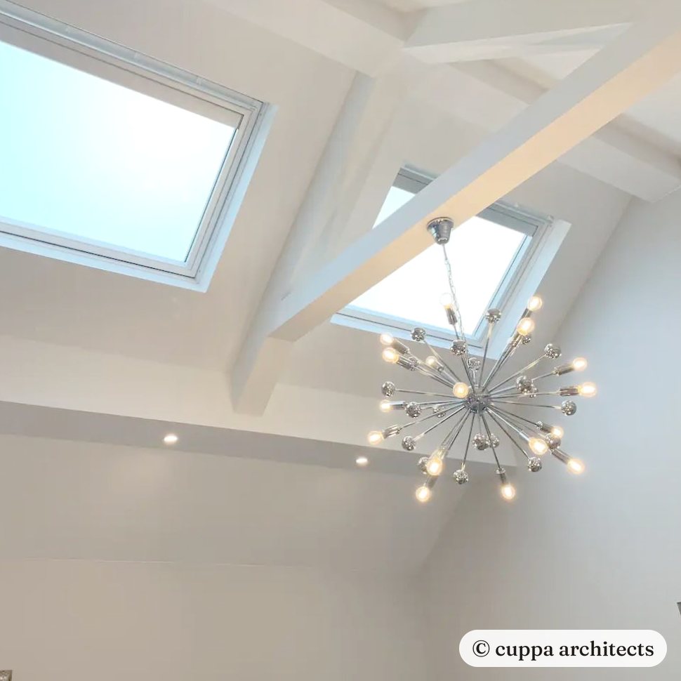 A vaulted ceiling with rooflights, a painted tie beam and a starburst pendant light