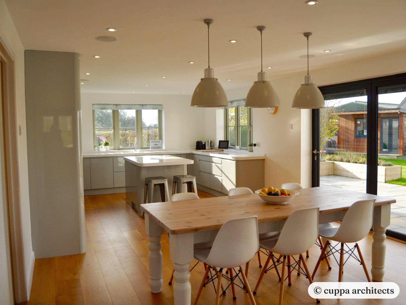 A farmhouse kitchen with pendant lights and sliding doors to the garden