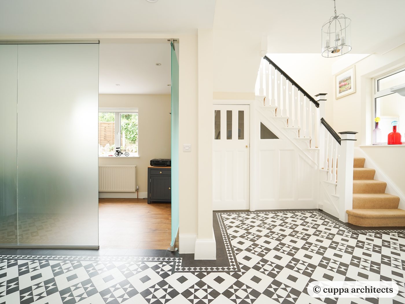 An entrance hall with patterned floor tiles, a new stair and a frosted glass partition