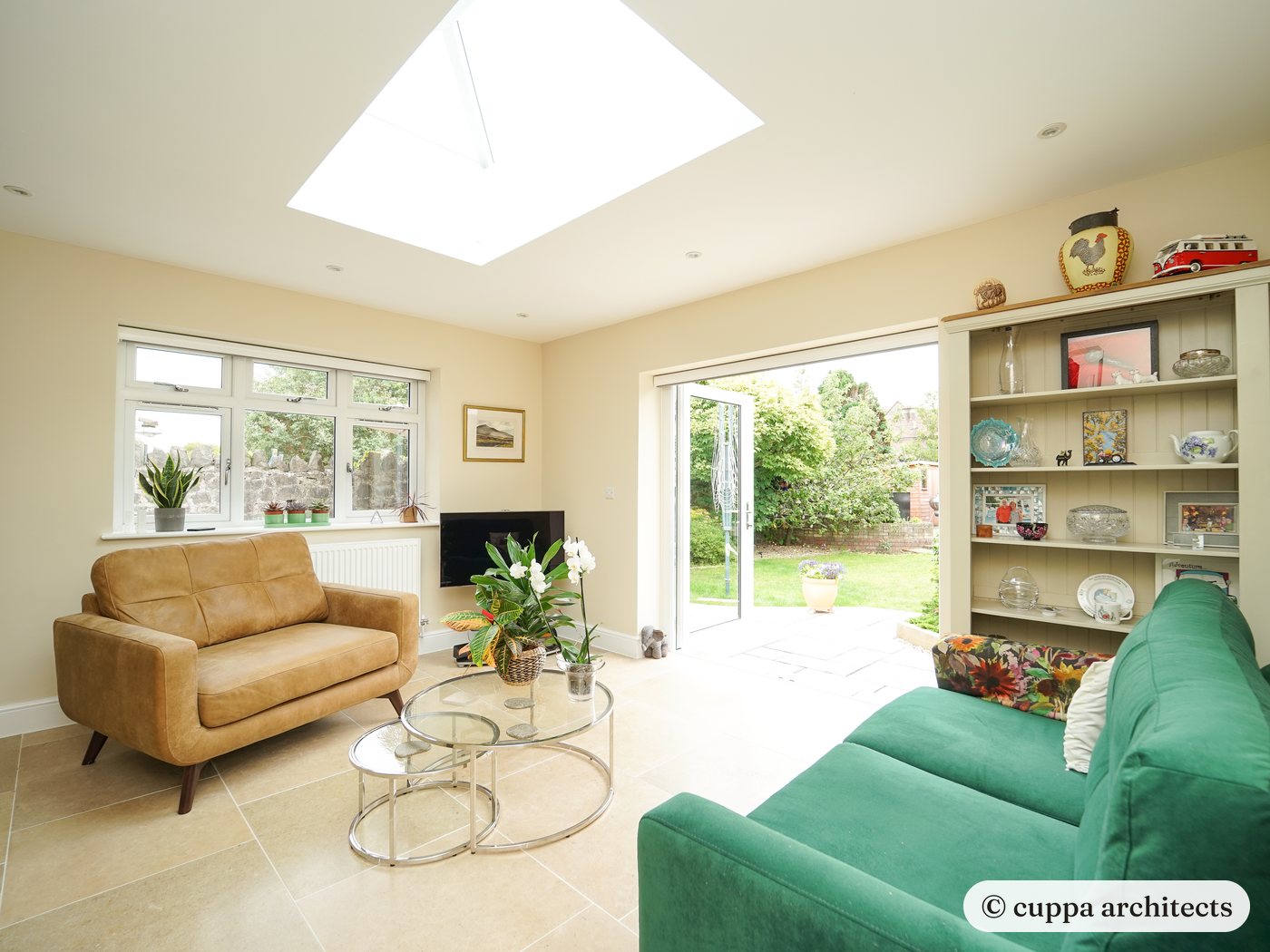 A bright living room with roof light, glazed doors to the garden and a green sofa