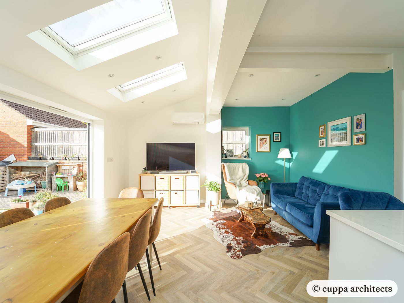 The living end of the extension with a velvet sofa and rooflights over the dining table
