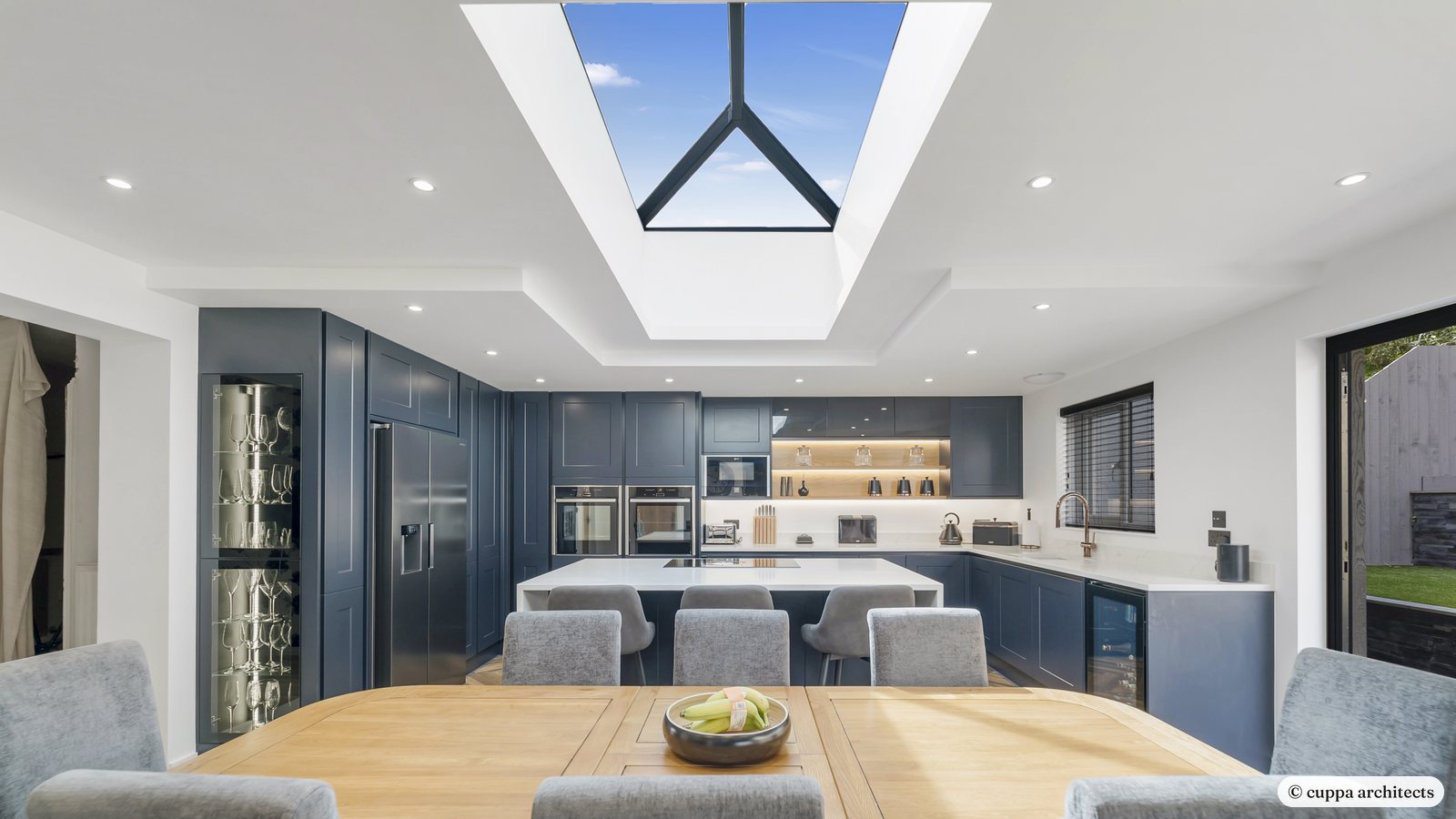 An open-plan kitchen and dining extension under a large roof lantern, with navy units and an island