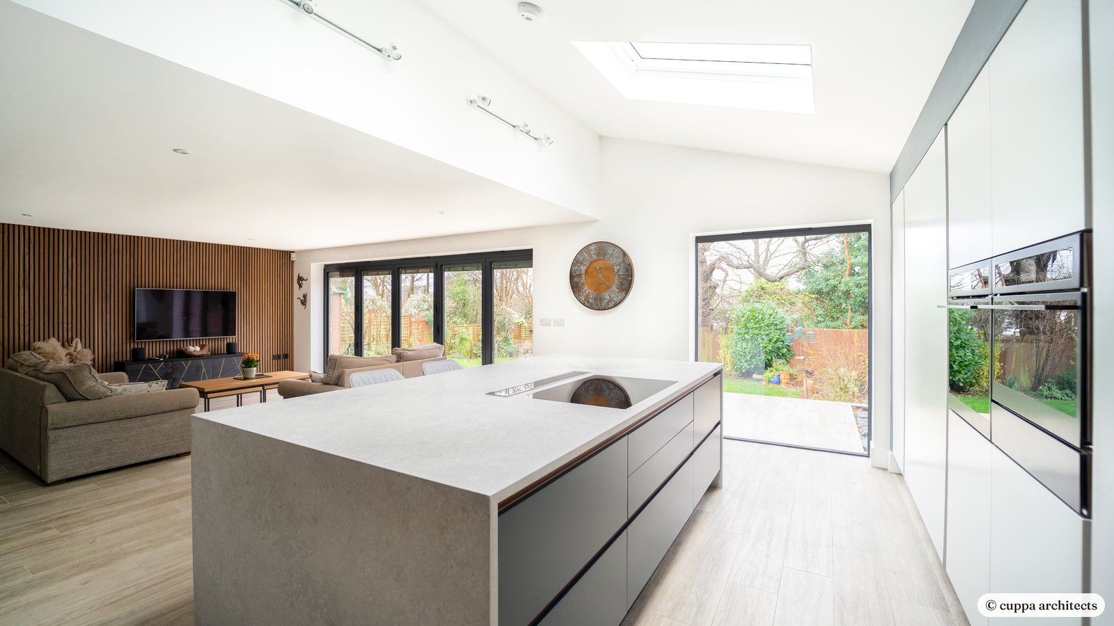 A long open-plan kitchen extension with a stone-effect island and glazed doors to the garden