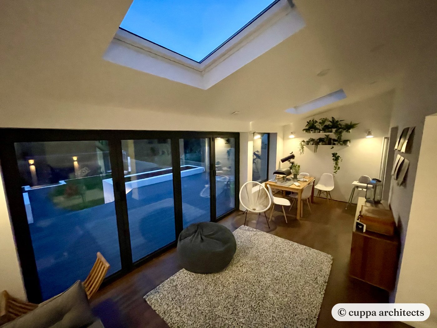 An extension with a large roof light and glazed doors, lit in the evening