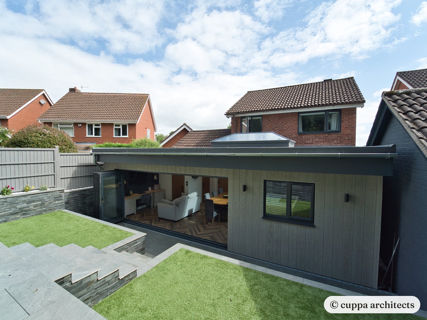 A dark-clad single storey extension set into a sloping garden