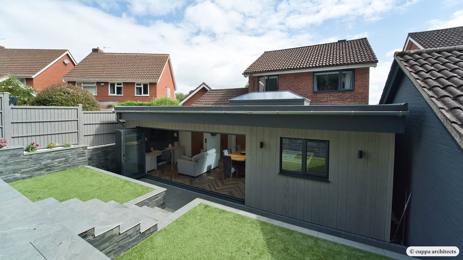 A dark-clad single storey extension set into a sloping garden