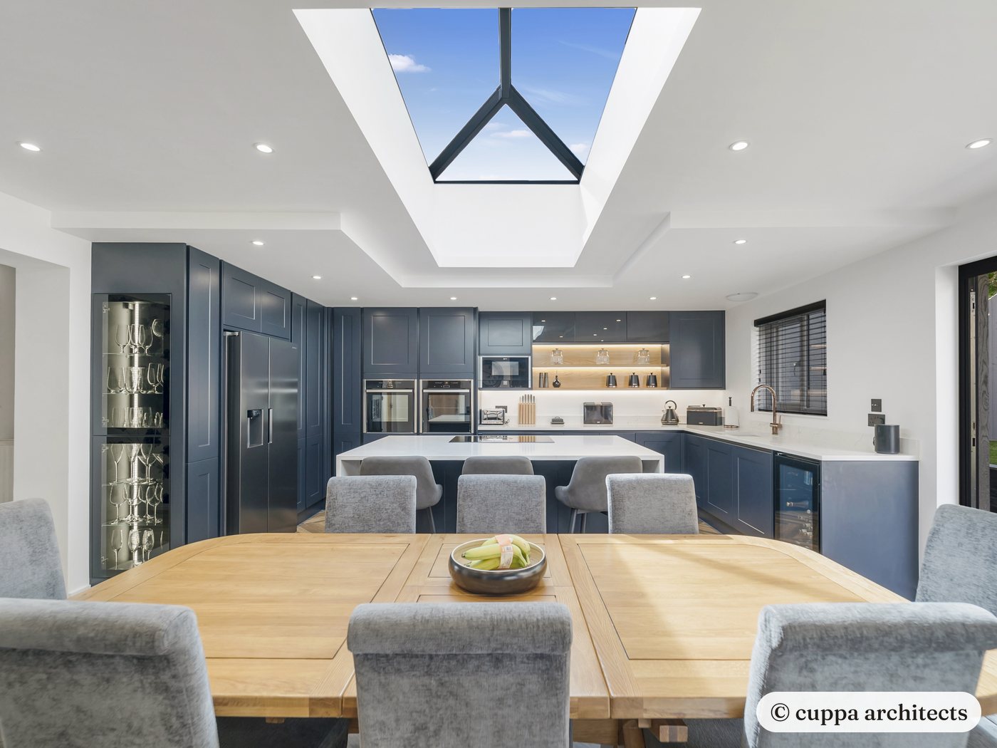 An open-plan kitchen and dining extension under a large roof lantern, with navy units and an island