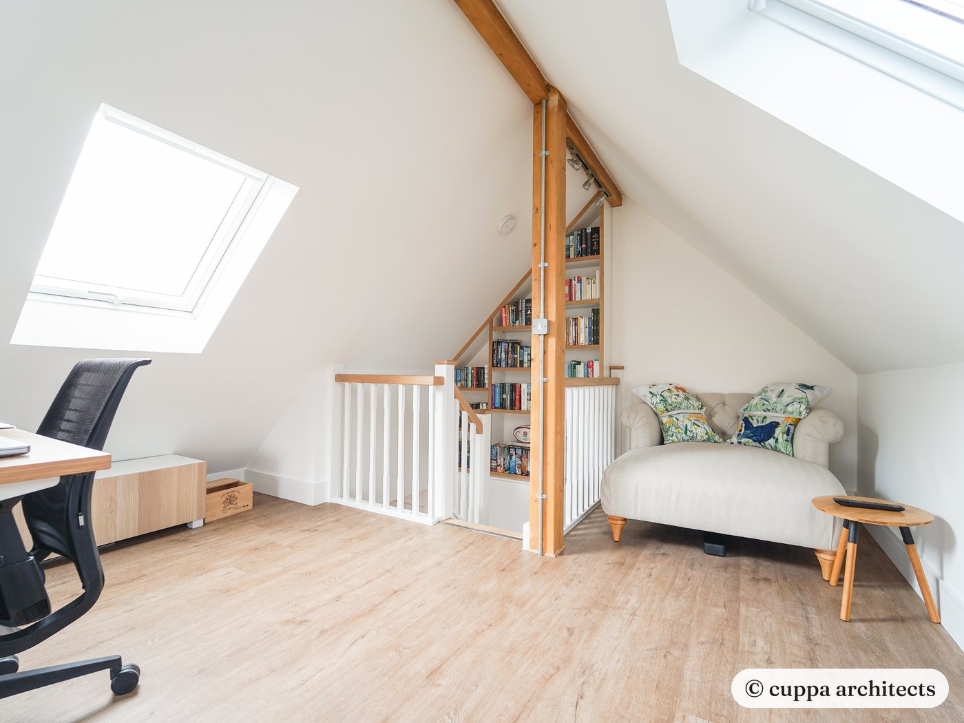 A bright room in the roof with roof windows, a desk and an open stair